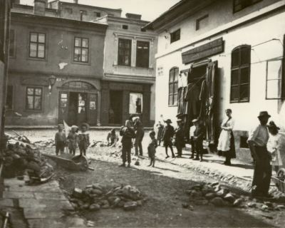 Čilý obchodní ruch v Radniční ulici ve Frýdku. Vpravo obchod konfekcí židovského obchodníka Berthold